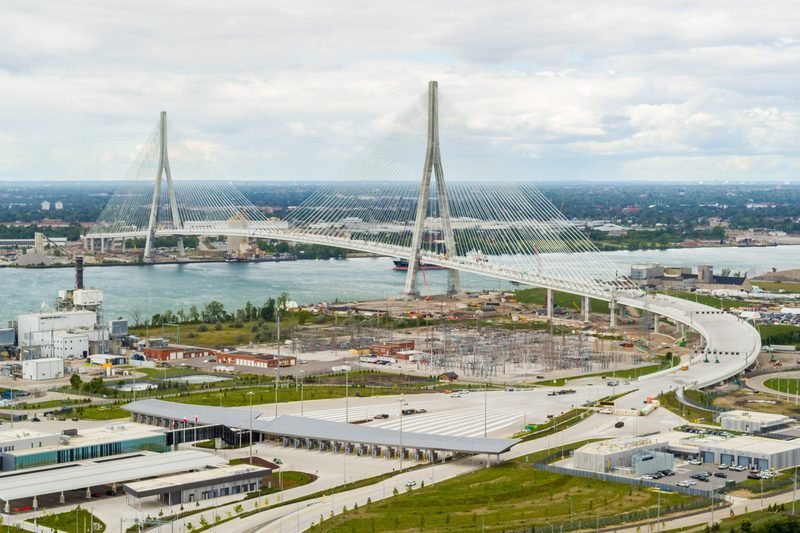 An aerial view of a cable-stayed bridge with two tall towers spanning a wide river