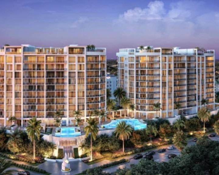 A rendering of two residential towers around a pool deck, lit at dusk